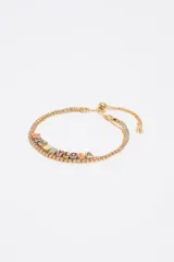 Pulsera de metal dorado con pedrería brillante y cubos esmaltados de colores que forman el logo de la marca Bimba y Lola. Cuenta con un sistema de cierre deslizante ajustable.