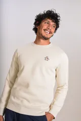 Buzo de cuello redondo color crudo, con detalle de logo bordado en el pecho, mangas largas y puños elastizados.