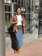 Falda midi de denim con elastano, corte recto y tajo frontal. Presenta bolsillos delanteros de cuero en color tostado y diseño clásico.