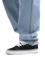 Pantalón jean celeste de corte amplio, estilo carpintero, con bolsillos laterales y traseros.