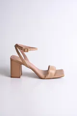 Sandalia de cuero color nude, con tira delgada sobre los dedos, pulsera al tobillo con hebilla y tacón cuadrado.