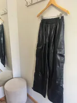 Pantalón cargo negro de cuero sintético, corte holgado, cintura elastizada y bolsillos laterales con solapa.