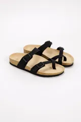 Sandalias planas de color negro con tiras ajustables mediante hebillas metálicas y diseño con separación para el dedo. Cuenta con plantilla acolchada y suela de corcho.