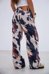 Pantalón de jean de tiro medio-bajo con corte recto y estampado tipo animal print de manchas irregulares en tonos beige, azul oscuro y terracota. Confeccionado en denim rígido sin elastano.
