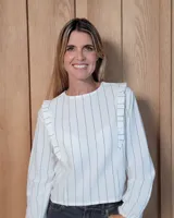 Blusa de manga larga con diseño a rayas verticales, cuello redondo y detalle de volados en los hombros.