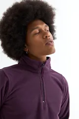 Buzo de polar color bordó, con cuello alto y cierre frontal parcial, de manga larga y diseño funcional con bolsillos laterales.