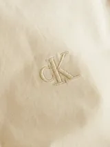 Camisa de manga larga color beige confeccionada en popelina de algodón, con cierre frontal con botones, puños con botones y logo Calvin Klein bordado en el pecho.