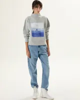 Buzo gris claro de algodón con cuello medio y estampa rectangular con diseño de paisaje marítimo en tonos azules.