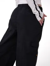 Pantalon cargo de corte relajado color negro, confeccionado en nylon. Presenta cintura elástica con cordón ajustable, bolsillos laterales y un bolsillo cargo con etiqueta de la marca en el lateral derecho.