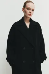 Abrigo largo de corte oversize con cuello de solapa, manga larga y cierre frontal cruzado con botones. Cuenta con bolsillos delanteros.