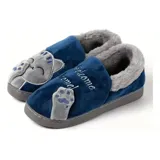 Pantuflas cerradas de color azul con diseño de gatito, confeccionadas en piel sintética suave con interior de peluche gris. Presentan un bordado con la frase 'Welcome Home' y apliques de patitas de gato. Cuentan con suela de goma antideslizante.