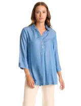 Blusa de lyocell color azul claro, con cuello camisero, escote en V y cierre frontal parcial con botones. Presenta mangas tres cuartos amplias y un corte holgado con aberturas laterales en el ruedo.