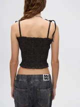 Top crop de tela denim con efecto fruncido, breteles finos ajustables con lazos y diseño entallado al cuerpo.