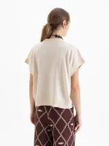 Chaleco de tejido de punto en color celeste, con cuello redondo y mangas cortas con terminación en rib. Presenta un diseño holgado con aberturas laterales en el ruedo y un pequeño bordado decorativo en la parte inferior.