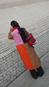 Mochila pequeña color borgoña con detalles en cuero marrón y aplique metálico de un caballo. Tiene manija superior y correas traseras regulables.