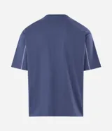 Remera de algodón color azul con corte boxy, cuello redondo y mangas cortas. Presenta una estampa frontal con lettering en color blanco y costuras decorativas en contraste a lo largo de las mangas.