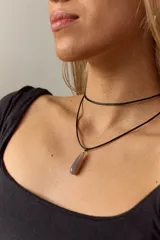 Gargantilla con tiento negro y dije de piedra natural en forma de gota con engarce de acero quirúrgico.