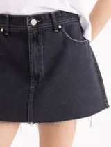 Minifalda de denim negro, de tiro medio/bajo y corte recto, con cinco bolsillos y ruedo desflecado al corte.