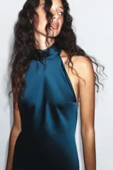Vestido largo de satén verde oscuro con cuello halter y lazada en el mismo tejido en la parte posterior, diseño sin mangas y espalda descubierta.