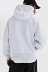 Canguro de felpa gris melange, con capucha de doble capa, bolsillo tipo canguro y estampado frontal con la leyenda 'SOHO NYC ATHLETICS DEPT' en color negro. Presenta hombros caídos y puños y bajo de punto acanalado.
