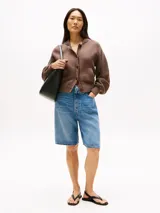 Pantalón corto de jean celeste, de corte recto y tiro medio. Con diseño de cinco bolsillos, cierre de cremallera y botón, y parche de logo Tommy Hilfiger en la parte posterior de la cintura.