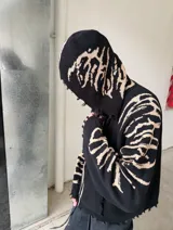 Hoodie con cierre frontal, confeccionado en tejido de punto 100% algodón. Es una prenda reversible con diseño de estampado gráfico en mangas y capucha, y presenta detalles de roturas intencionales en puños, ruedo y bolsillos.