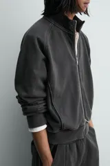 Sudadera de algodón con interior en rizo afelpado, cuello subido, manga larga y cierre frontal de cremallera. Presenta un efecto lavado que le da una apariencia única y bolsillos frontales ocultos en las costuras.