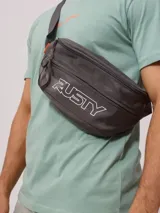 Riñonera Rusty modelo Skati color gris oscuro, con compartimento principal y bolsillo frontal con cierre, correa ajustable y logo de la marca estampado en blanco.