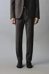 Pantalón de traje de corte regular fit, confeccionado en lana de origen italiano. Presenta un diseño a cuadros sutiles, bolsillos delanteros, bolsillos traseros de doble vivo con botón y cierre frontal con cremallera y botón.
