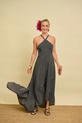 Vestido largo asimétrico color negro con estampado de lunares blancos, escote halter cruzado al frente y diseño con espalda descubierta.