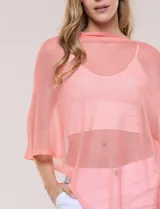 Poncho liviano de tejido de punto fino calado, color blanco, con silueta asimétrica envolvente, escote bote drapeado y mangas integradas estilo capa.