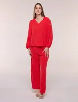 Blusa azul de corte holgado y fluido, con escote en V y mangas largas raglán que presentan detalles de calados con forma de flores y puños elastizados.
