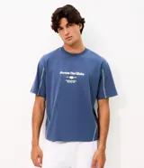 Remera de algodón color azul con corte boxy, cuello redondo y mangas cortas. Presenta una estampa frontal con lettering en color blanco y costuras decorativas en contraste a lo largo de las mangas.