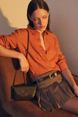 Cinturón de cuero liso color marrón oscuro con hebilla plateada y pasador metálico decorativo.