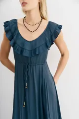 Vestido largo negro de escote redondo con volados decorativos que recorren el frente y la espalda. Presenta un cordón de ajuste en la cintura con terminaciones metálicas y espalda baja.