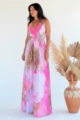 Vestido largo sin mangas con escote en V pronunciado, de corte amplio y fluido, con estampado abstracto en tonos rosados, marrones y blancos, y un cordón trenzado ajustable en la cintura.