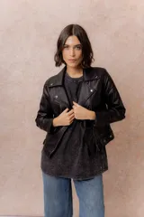 Campera tipo biker de eco cuero negro, con cierre frontal asimétrico, cuello con solapas y broches metálicos, y bolsillos con cierre.