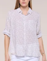 Camisa holgada de algodón liviano con estampa botánica en tonos beige y blanco, cuello camisero y mangas largas.