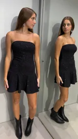 Vestido corto strapless negro con acabado brillante de lurex, corte ajustado en el torso y falda con vuelo.