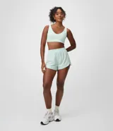 Bermuda deportiva femenina modelo runner color verde menta, con cintura elástica y diseño holgado con bajo redondeado.