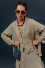 Chaqueta de lino color beige, de calce relajado, con escote en V, cierre frontal con botones y bolsillos frontales aplicados.