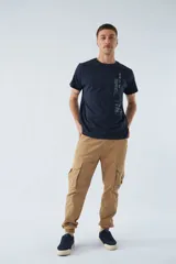 Pantalón cargo color beige, corte slim, con bolsillos laterales con botón, cierre con botón y puños en los tobillos.