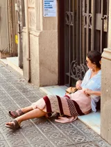 Pollera larga tejida a rayas horizontales en tonos rosa, blanco y borgoña, con detalles de crochet y tajos laterales.