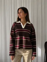 Sweater de punto con diseño a rayas horizontales en tonos marrón, bordó y crema. Presenta cuello polo con solapas en color crema, manga larga y corte holgado.