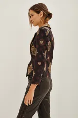 Saco de corte sastre con solapas anchas, confeccionado en algodón con estampado étnico en tonos oscuros y dorados. Presenta cierre frontal y diseño estructurado.