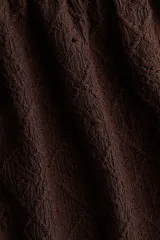 Blusa marrón de punto pointelle con textura, escote corazón, detalle cut-out con cordón de ajuste en el busto, mangas cortas circulares con volados y diseño acampanado.