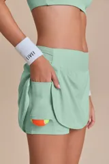 Pollera deportiva color rosa fucsia, con estampado en relieve de texto. Es de corte corto con ruedo redondeado y cuenta con shorts internos.