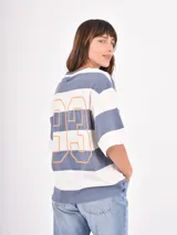 Remera de corte holgado con diseño de rayas horizontales anchas en tonos azul y blanco, cuello redondo y mangas cortas.