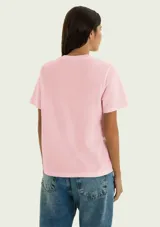 Remera blanca de manga corta y cuello redondo, confeccionada en algodón, con un pequeño estampado floral en el pecho.
