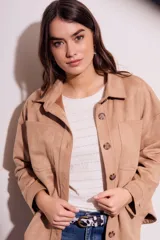 Sobrecamisa negra de estilo shacket, confeccionada en tejido de gamuza sintética. Presenta cuello camisero, cierre frontal de botones y dos bolsillos de parche con solapa en el pecho. El calce es oversize y las mangas son largas.